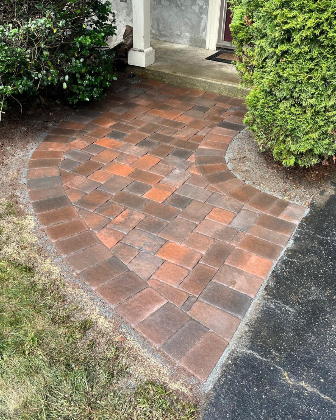 Close-up of a custom-built walkway with paver stones leading to a front entrance, designed by Marcelino Hardscaping. Serving Central Massachusetts, the Metrowest region, and parts of Greater Boston.